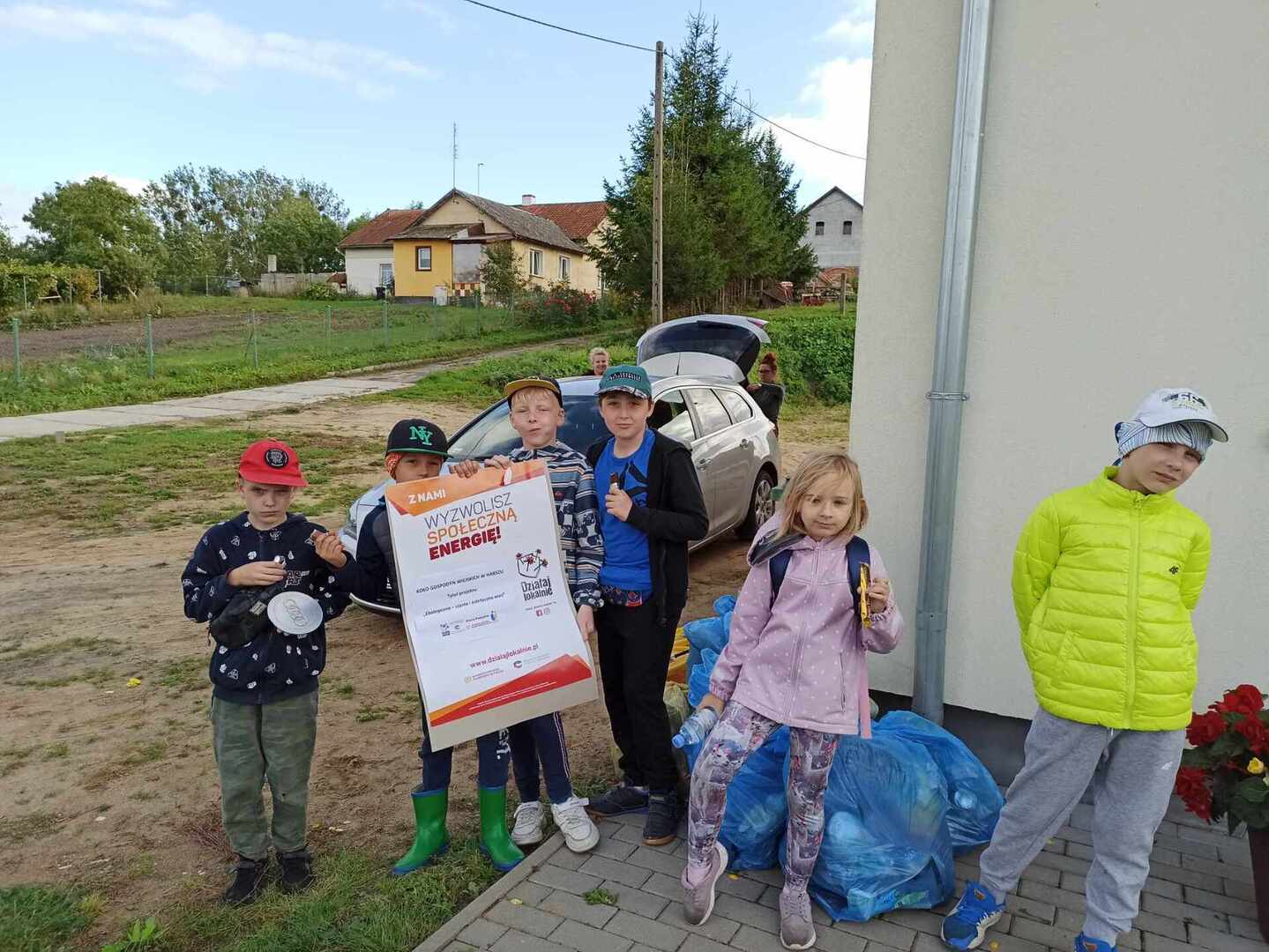 na zdjęciu uczestnicy projektu, chłopcy trzymają w ręku plakat informujący o projekcie