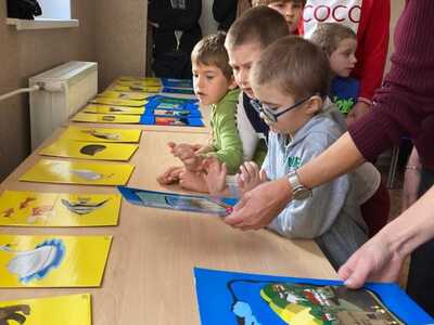 uczniowie stoją przed ławką, na której rozłożone są kartki