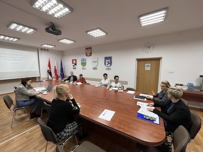 członkowie Rady siedzą przy stole w Sali konferencyjnej