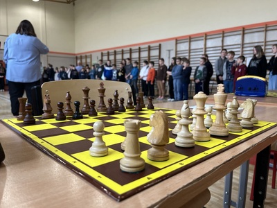 na pierwszym planie szachownica w tle uczestnicy mistrzostw