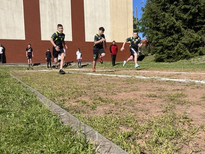 trzech chłopców podczas biegu w tle pozostali zawodnicy 