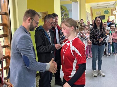 dyrektor szkoły SP Sobiechy wręcza medal zwyciężczyni w tle sędzia zawodów