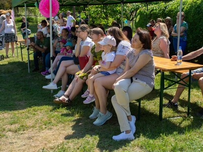 na zdjęciu goście siedzący na ławkach w tle krzewy