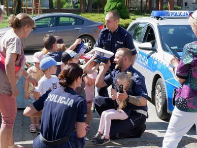 na zdjęciu uczniowie zakładają czapki funkcjonariuszy policji