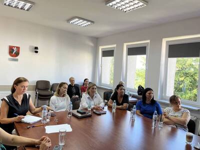 uczestnicy spotkania siedzą przy stole w sali konferencyjnej 