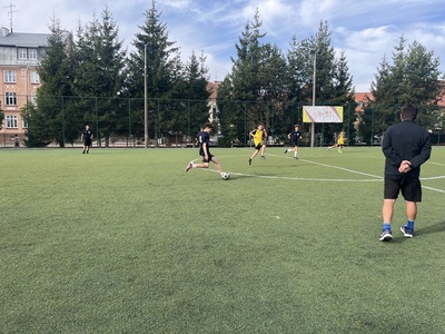 zawodnicy podczas rozgrywek, w tle budynek szkoły