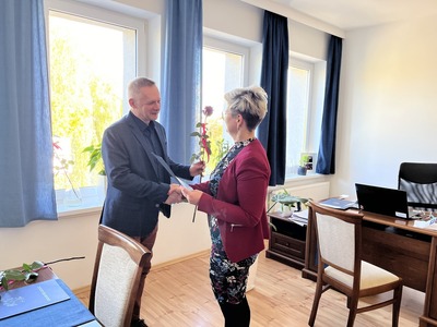 na zdjęciu Alicja Rymszewicz wręczająca kwiat oraz podziękowania dla Andrzeja Raczkowskiego Dyrektora SOSW w Węgorzewie, w tle okna