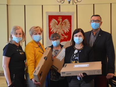 Zdjęcie przedstawia moment przekazania laptopów Na zdjęciu od lewej znajdują się cztery osoby: Agnieszka Jakubowska -  Kierownik Zespołu Ekonomiczno-Administracyjnego Szkół, Ewa Nieweś - Wicedyrektor Szkoły Podstawowej w Brzezinach, Elżbieta Plewińska - Dyrektor Szkoły w Sobiesękach, Maria Więcław - Dyrektor Szkoły Postawowej w Brzezinach oraz Wójt Gminy Brzeziny Marek Cieślarczyk