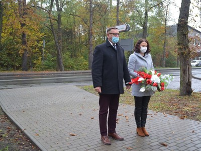 Wójt Gminy Brzeziny Marek Cieślarczyk z Panią Kamilą Biernacik składają kwiaty w kolorze biało-czerwonym przy pomniku upamiętniającym żołnierzy z tereny gminy Brzeziny poległych podczas II Wojny Światowej 