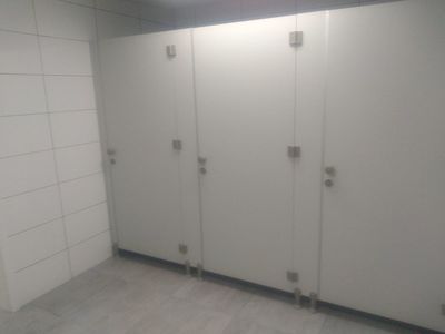 trzy pary drzwi w kolorze białym do kabin z ubikacjami
