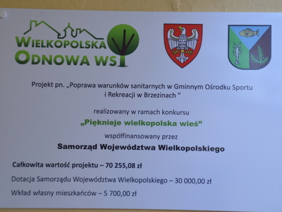 tablica informacyjna o tytule projektu, przez jaką instytucję dofinansowany oraz informująca o kosztach realizacji remontu łazienek w GOSiR W Brzezinach  