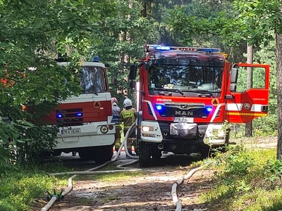 samochody pożarnicze w lesie, strażacy z wężami