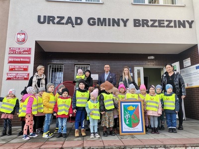 Dzieci, nauczyciele, wójt przed budynkiem Urzędu Gminy Brzeziny