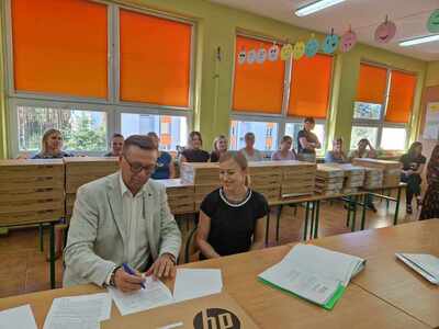 wójt podpisuje umowy na przekazanie laptopów