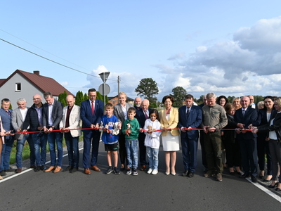 goście przecinający wstęgę na drodze