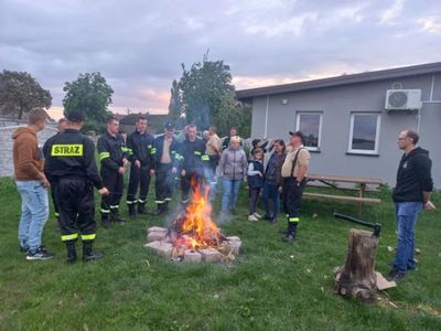 Zdjęcie przedstawia mieszańców sołectwa Łomów, którzy pieką kiełbaski przy ognisku.