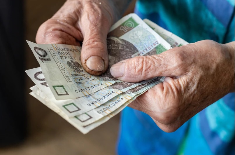 Osoba trzyma w rękach banknoty dziesięcio złotowe.