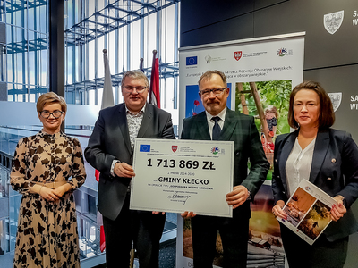 Burmistrz Gminy Kłecko wraz z Skarbnik, odbierają z rąk wicemarszałka symboliczny czek