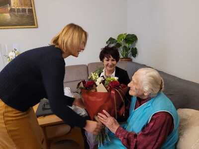 Pani Kierownik USC wręcza kwiaty stulatce