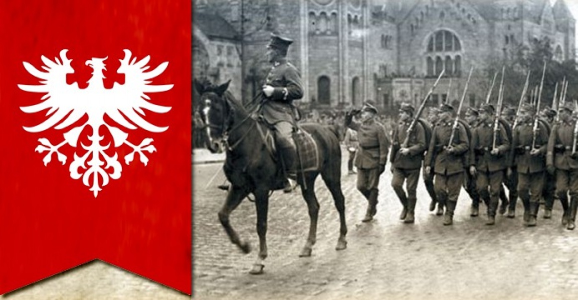 Historyczna fotografia żołnierzy maszerujących ulicą obok jeźdźca na koniu, obok czerwony sztandar z białym orłem.