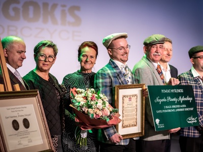 Członkowie Zarządu Powiatu Myślenickiego na Jubileuszu 50-lecia Kapeli Werdebusy Dobczyckie, stoją na scenie trzymając nagrody