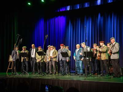 Jubileuszowy Koncert Kapeli Werdebusy Dobczyckie w RCOS, zespół stoi na scenie na tle niebieskich kotar