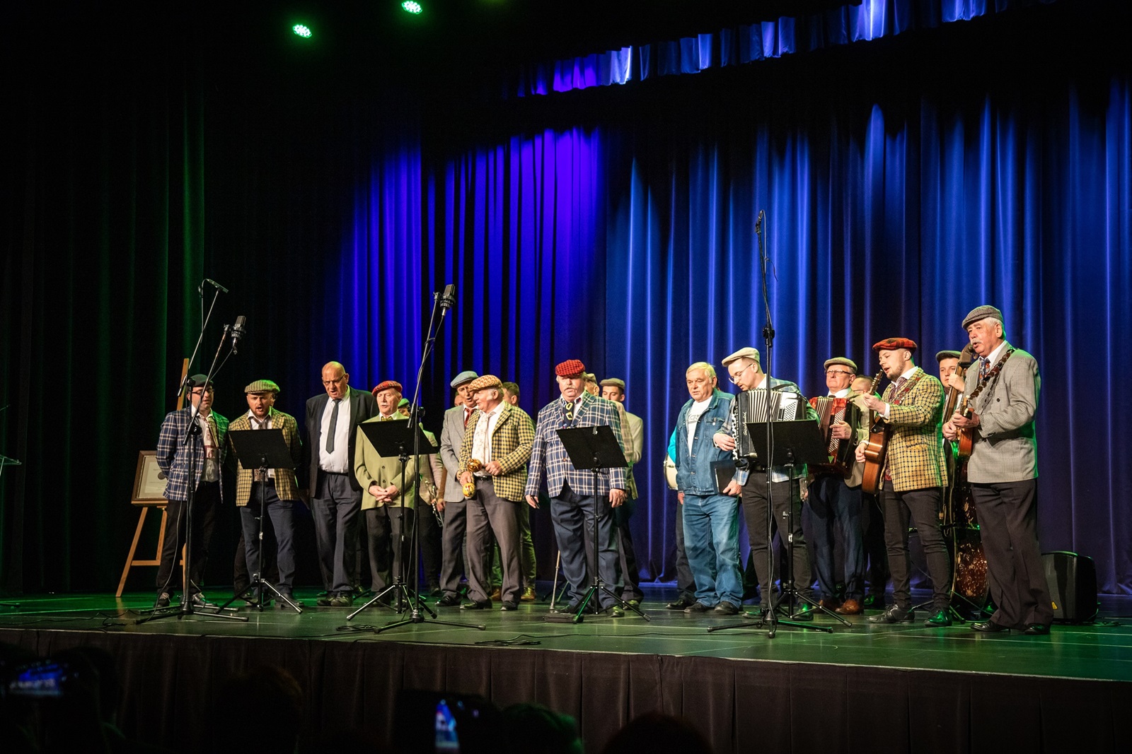 Jubileuszowy Koncert Kapeli Werdebusy Dobczyckie w RCOS, zespół stoi na scenie na tle niebieskich kotar 
