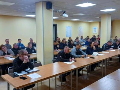 Liczna grupa uczestników siedzi w sali konferencyjnej, słucha prelekcji i robi notatki.
