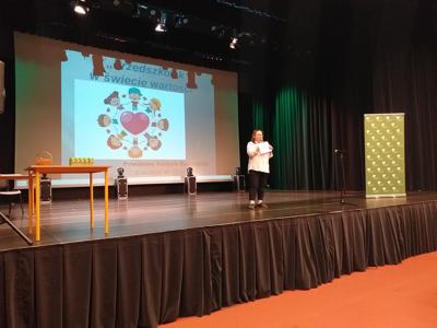 Kobieta na scenie podczas Powiatowego Konkursu Recytatorskiego „Przedszkolak w świecie wartości”.