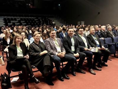 Uczestnicy konferencji klimatycznej siedzący w pierwszych rzędach sali, w tle widoczna liczna publiczność.