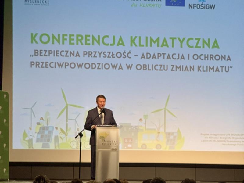Zdjęcie z konferencji klimatycznej „Bezpieczna przyszłość – adaptacja i ochrona przeciwpowodziowa w obliczu zmian klimatu”, mówca przy mównicy.