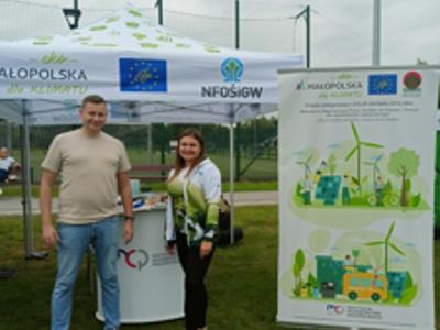 Stoisko projektu „Małopolska dla Klimatu” z namiotem i roll-upem informacyjnym, obsługiwane przez dwie osoby podczas wydarzenia plenerowego.