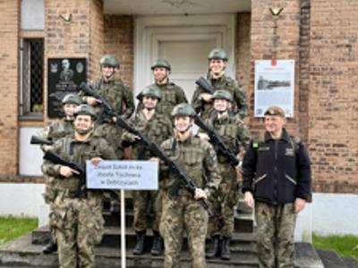 Uczniowie Zespołu Szkół im. ks. Józefa Tischnera w Dobczycach w strojach wojskowych pozują do pamiątkowego zdjęcia przed historycznym budynkiem.