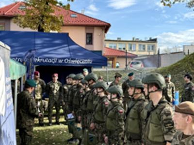 Uczniowie klas mundurowych stoją w szeregu podczas apelu, otrzymując nagrody i gratulacje od przedstawicieli wojska.