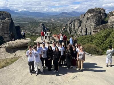 Grupa uczniów z opiekunkami na tle skalnych klasztorów Meteory w Grecji.