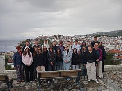 Grupa uczniów z opiekunkami na tle panoramy nadmorskiego miasta.