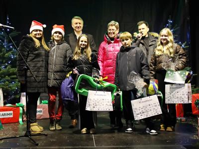 Scena na czarnym tle w świątecznej scenerii – starosta, doradcy, konferansjer oraz laureaci konkursu z nagrodami.