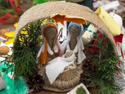 Stroik świąteczny- szopka z gałązek i sznurka, w tle inne ozdoby świąteczne