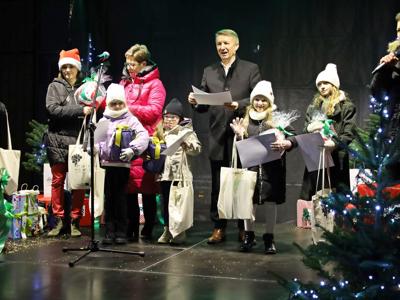 Starości na scenie z czarnym tłem wśród 4 dzieci nagrodzonych w konkursie, po bokach konferansjer i kobieta 