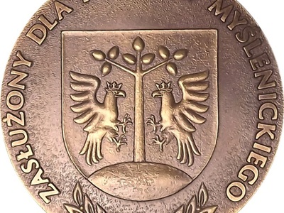 Logo z napisem: Zasłużony dla Powiatu Myślenickiego