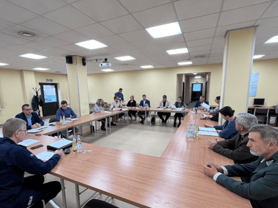 Zdjęcie z zebrania przy dużym stole w sali konferencyjnej. Uczestnicy siedzą, omawiając kwestie związane z bezpieczeństwem.
