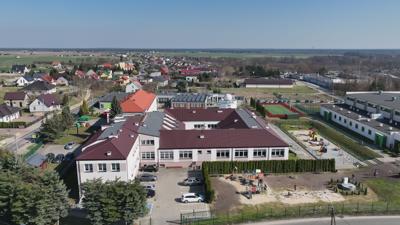 Widok na kompleks budynków sportowych, szkoły podstawowej, przedszkola, żłobka, biblioteki oraz astrobazy w Gostycynie.