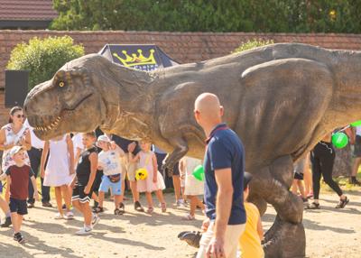 Na zdjęciu widać Dinozaura Rexa w tle mieszkańców