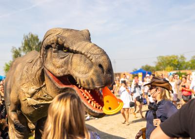 Na zdjęciu widać Dinozaura Rexa w tle mieszkańców