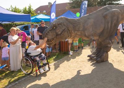 Na zdjęciu widać Dinozaura Rexa w tle mieszkańców