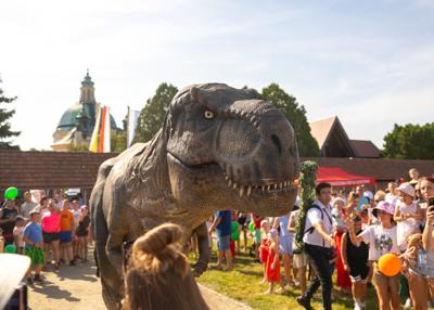 Na zdjęciu widać Dinozaura Rexa w tle mieszkańców