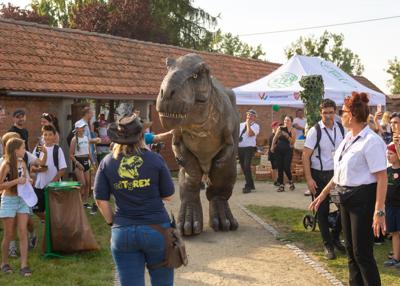 Na zdjęciu widać Dinozaura Rexa w tle mieszkańców