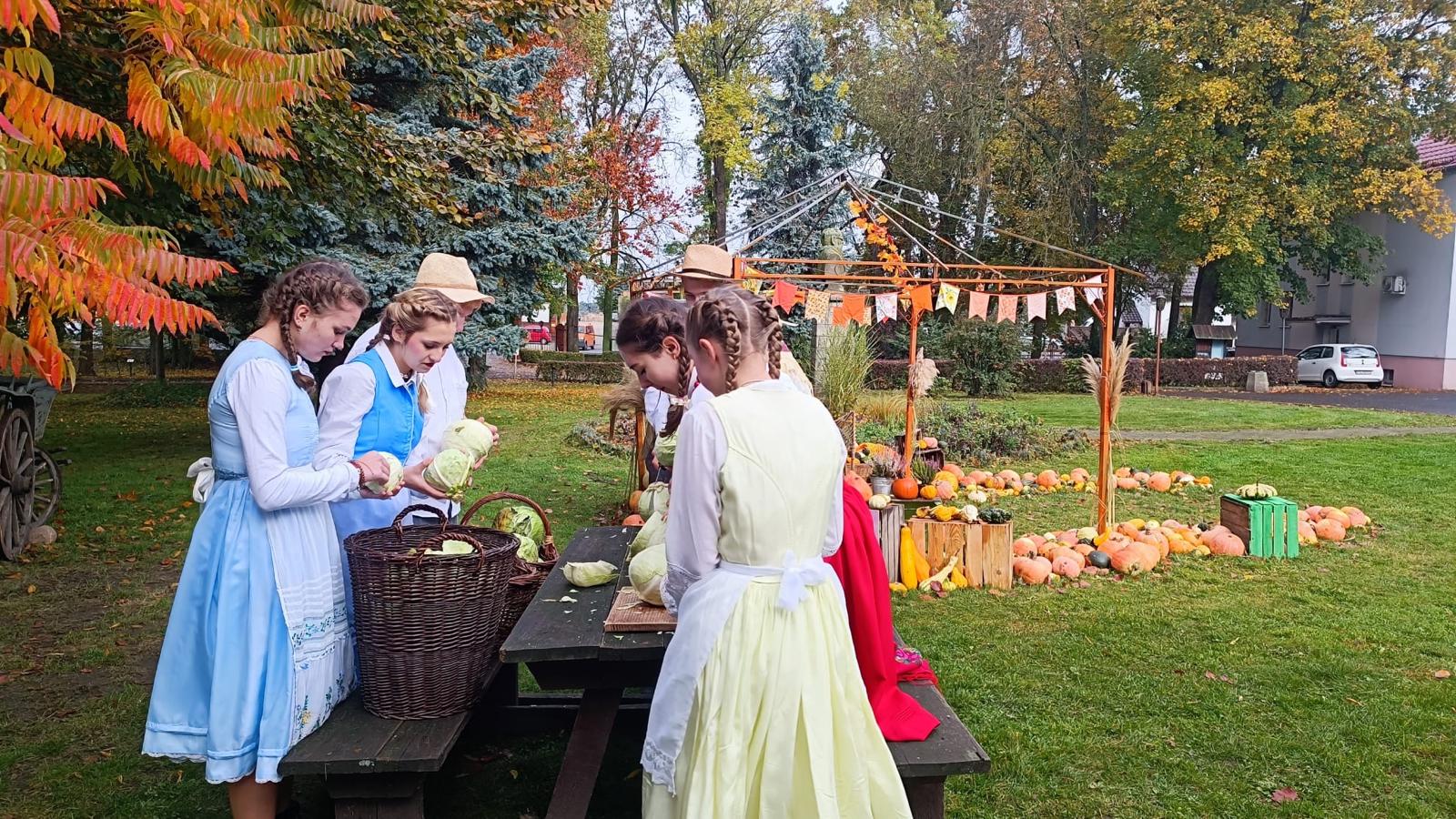 Zdjęcie przedstawia uczniów w strojach ludowych przy stole.