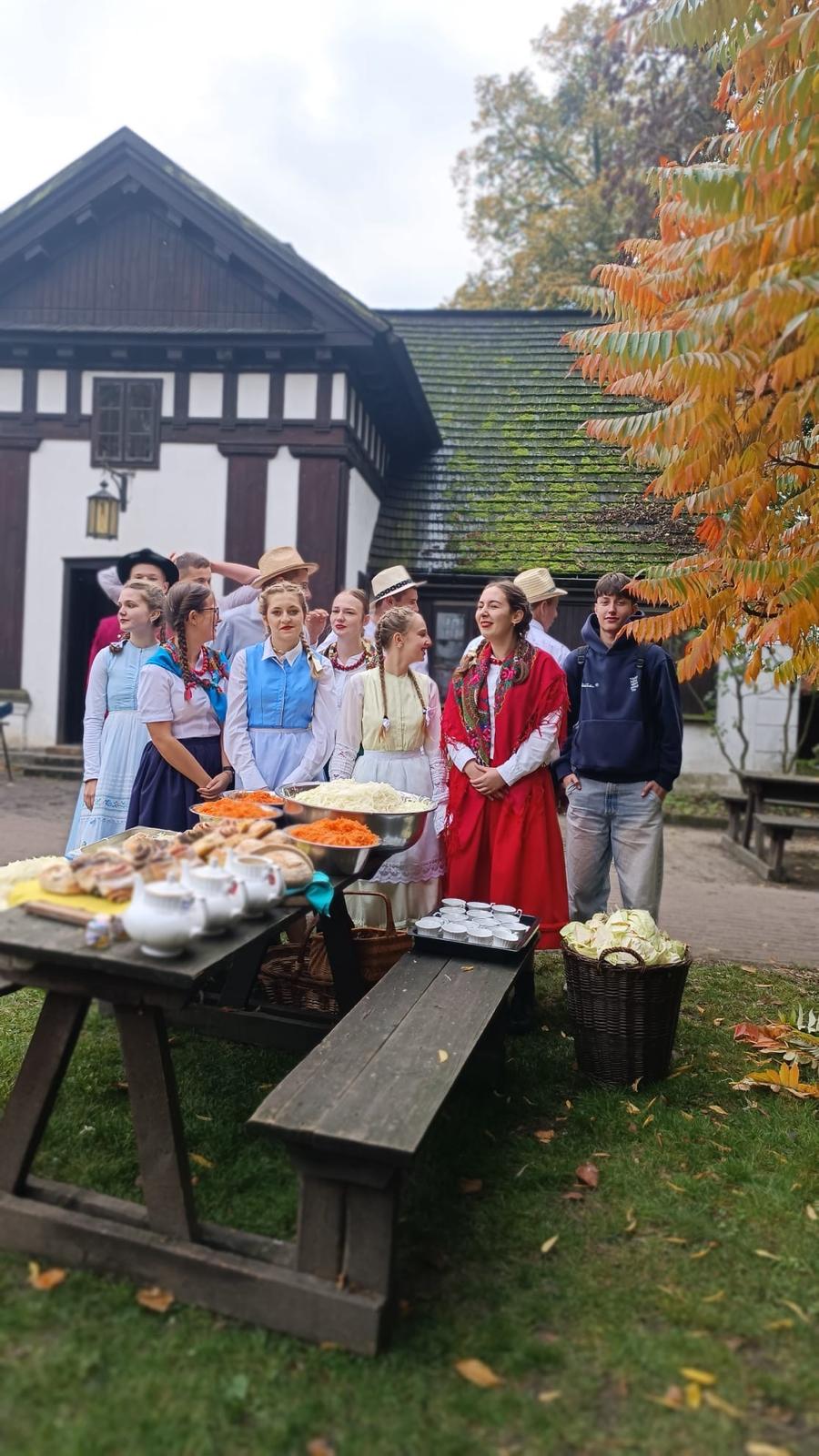 Zdjęcie przedstawia uczniów w strojach ludowych oraz stół przed nimi.