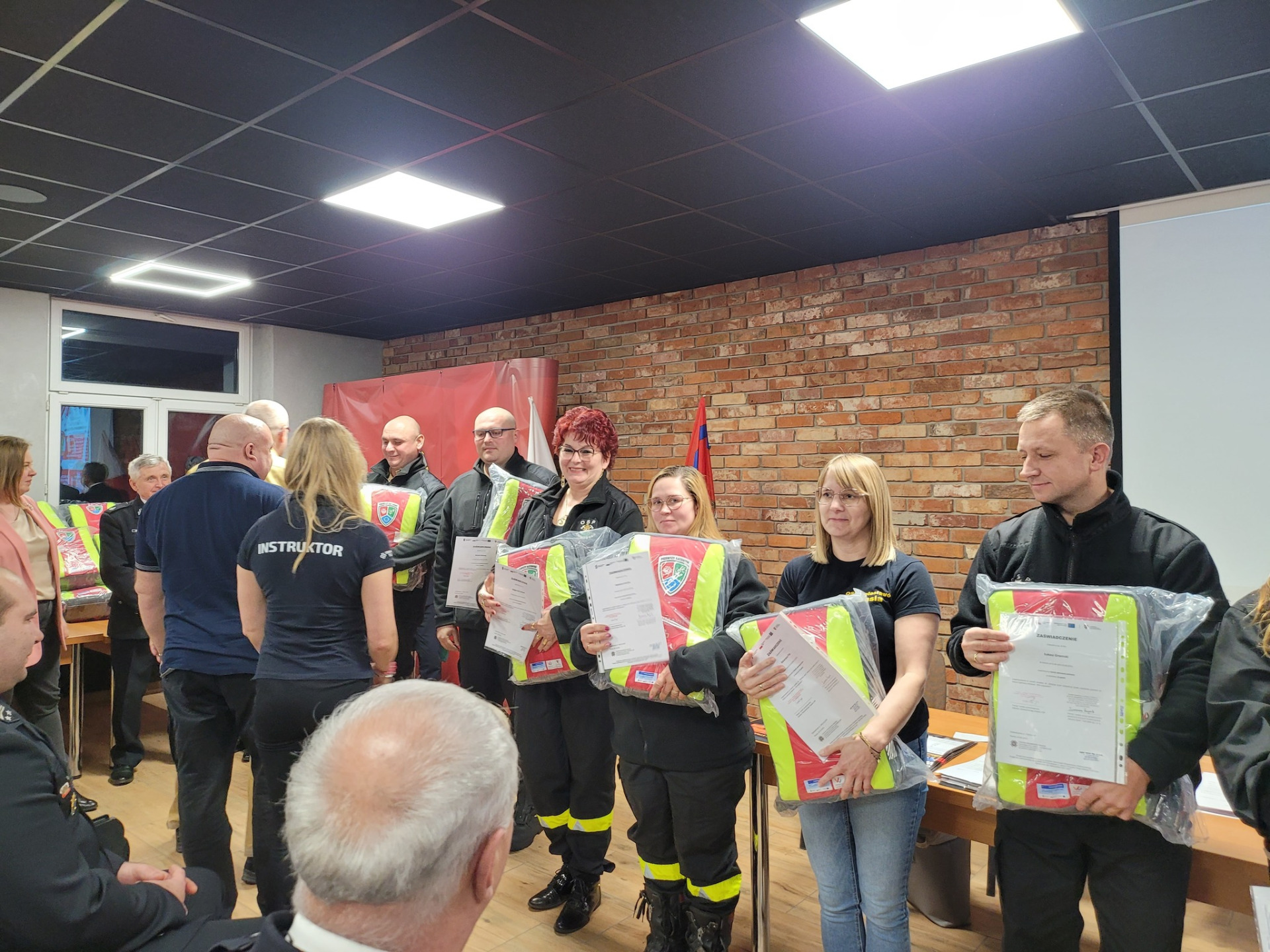 Zdjęcie przedstawia druhny i druhów z plecakami Pierwszego Ratownika i osoby je wręczające .jpg [1920x1440]